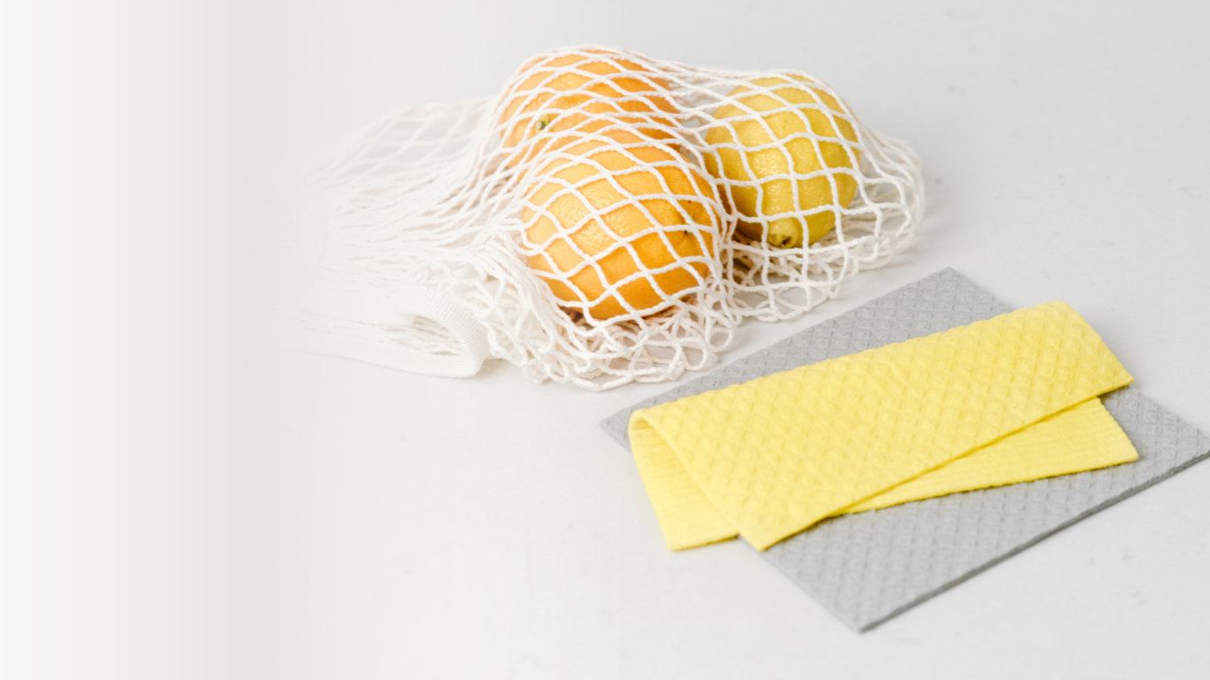 Nature Circle Swedish cloth in color yellow folded on top of grey Swedish dish cloth with a mesh bag of oranges in background